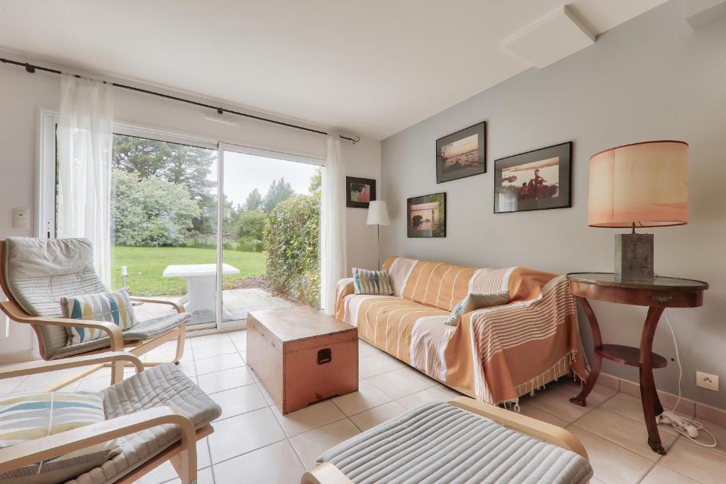 un salon avec un canapé, des chaises et une fenêtre dans l'établissement Jolie maison pour 5 - Pointe de Kerners Arzon, à Arzon