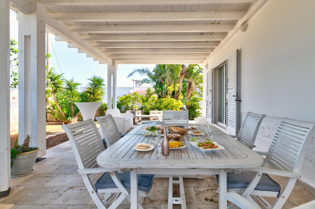 Una mesa de madera en un patio con sillas. en Villa Bianca Marina, en Villanova di Ostuni