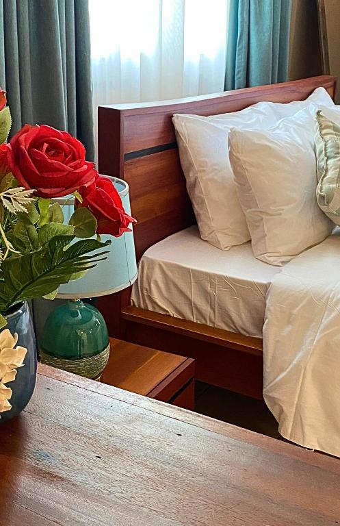 a bedroom with a bed and a vase with a red rose at Sunny Shore B&B in Dar es Salaam