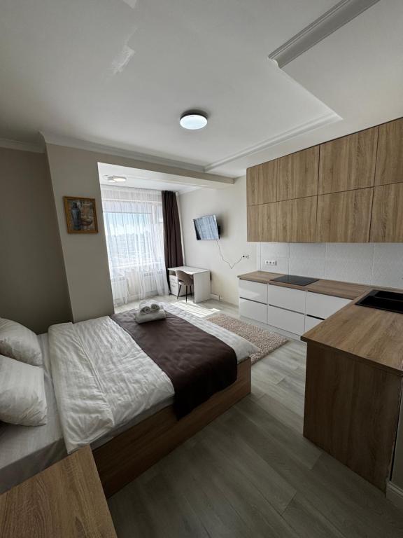 a bedroom with a large bed and a desk at Уют студия in Astana