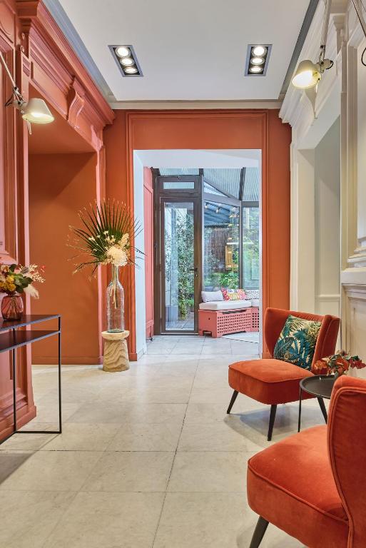 a lobby with orange walls and orange chairs at Hotel Cervantes by Happyculture in Paris