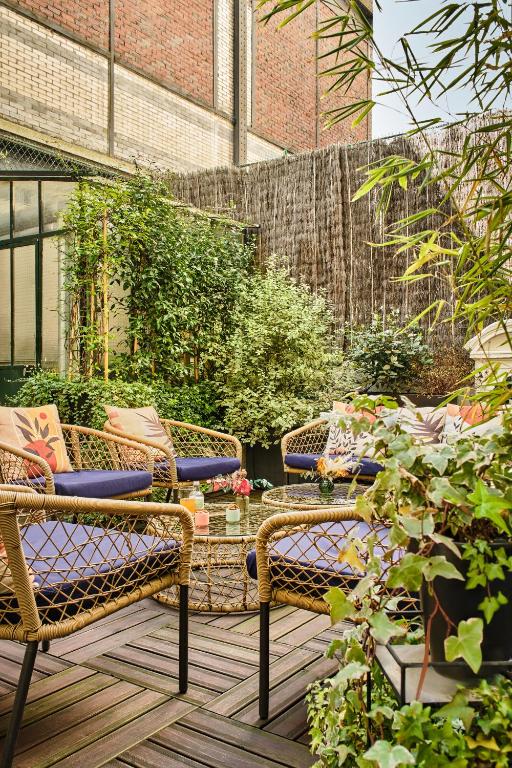 a patio with two wicker chairs and a table at Hotel Cervantes by Happyculture in Paris