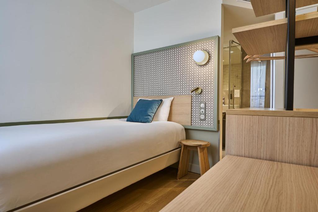 a bedroom with a large bed with a blue pillow at Hotel Cervantes by Happyculture in Paris