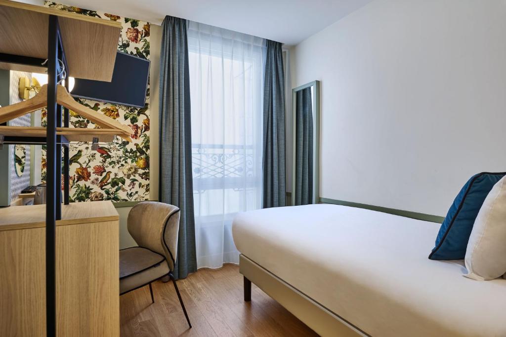 a hotel room with a bed and a desk and a window at Hotel Cervantes by Happyculture in Paris