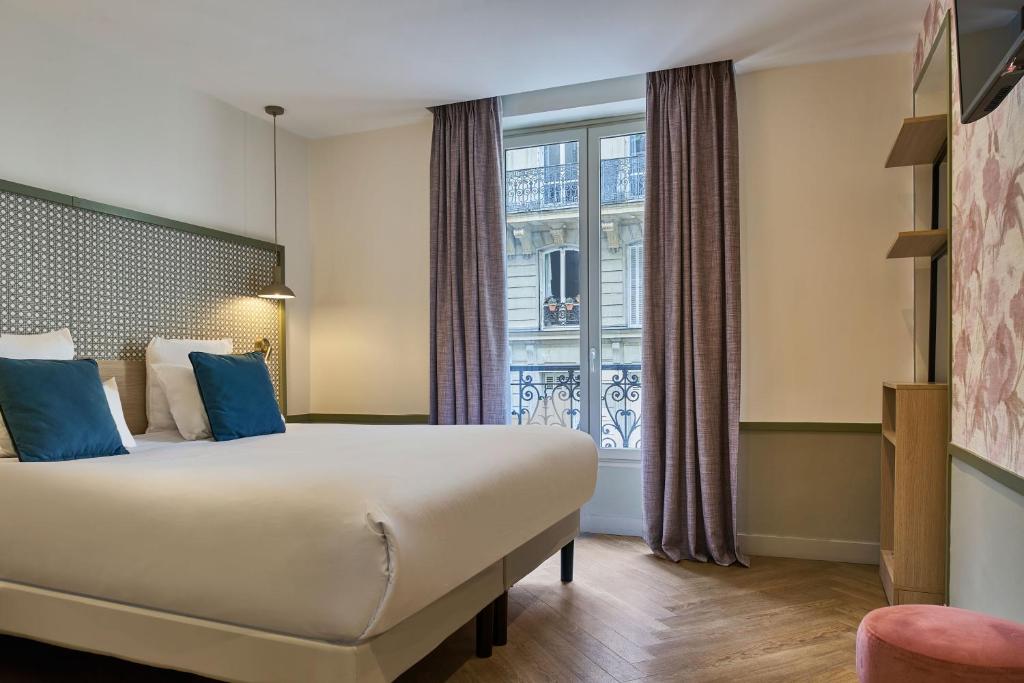 a hotel room with a bed and a window at Hotel Cervantes by Happyculture in Paris
