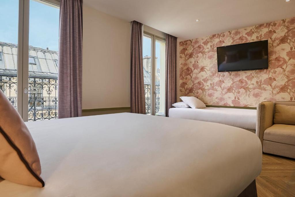 a hotel room with a bed and a tv at Hotel Cervantes by Happyculture in Paris