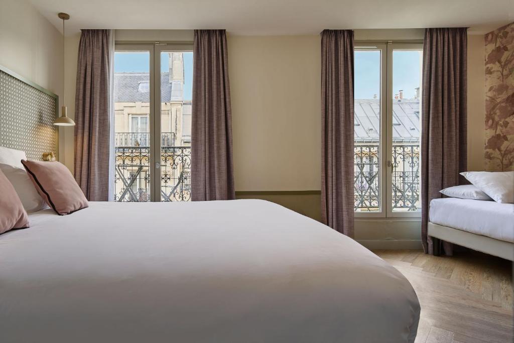 a bedroom with a large white bed and a balcony at Hotel Cervantes by Happyculture in Paris