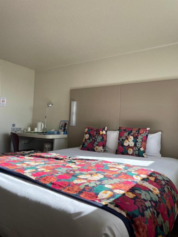 a bedroom with a bed with a colorful quilt on it at Brit Hotel Quimper Sud in Quimper