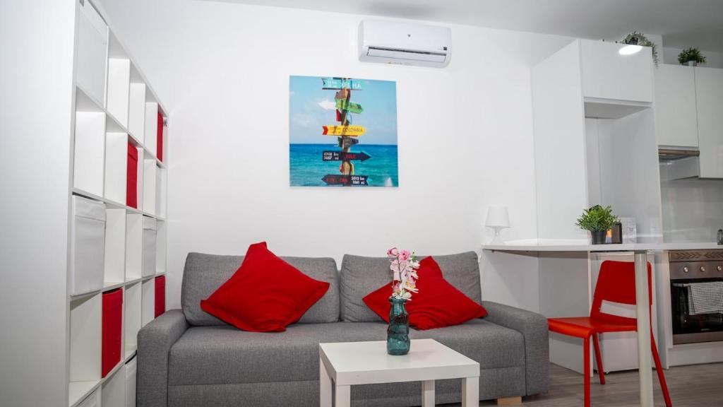 a living room with a grey couch and red pillows at Studio 1 Soto Parking Renfe in Torrejón de Ardoz