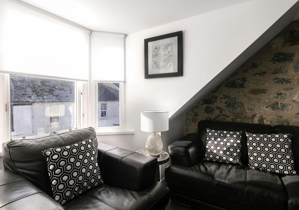 a living room with two leather chairs and a couch at Castle Street Apartments - Luxury Kilchattan Apartment in Rothesay