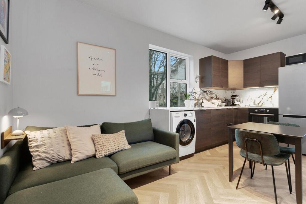 a living room with a green couch and a kitchen at New Charming Apartment in Reykjavík