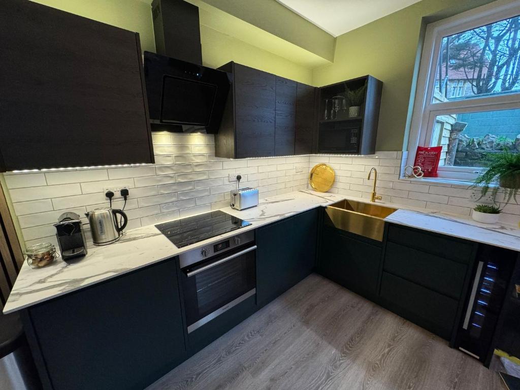 a kitchen with black cabinets and a sink at Brean Views in Weston-super-Mare