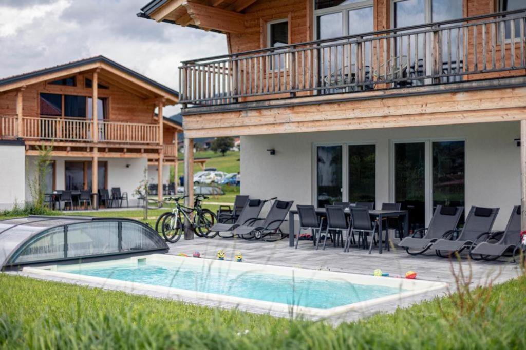 a house with a pool and chairs and a table at Luxalps- Chalets Inzell- Sauna- Skifahren- Wandern- Natur- Chiemgau Card in Inzell