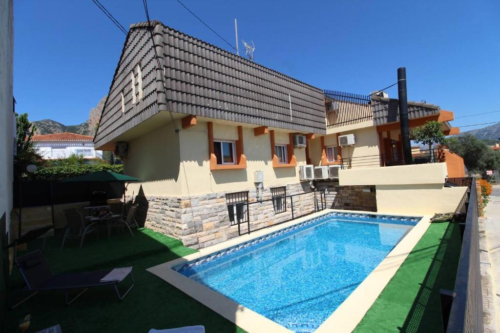 a villa with a swimming pool in front of a house at Chalet con piscina y barbacoa in Polop