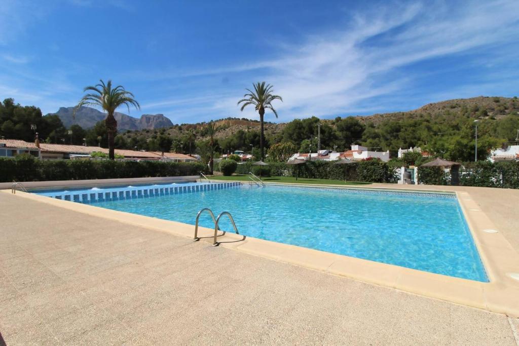 a swimming pool in a resort with palm trees at Casita con piscina comunitaria in La Nucía