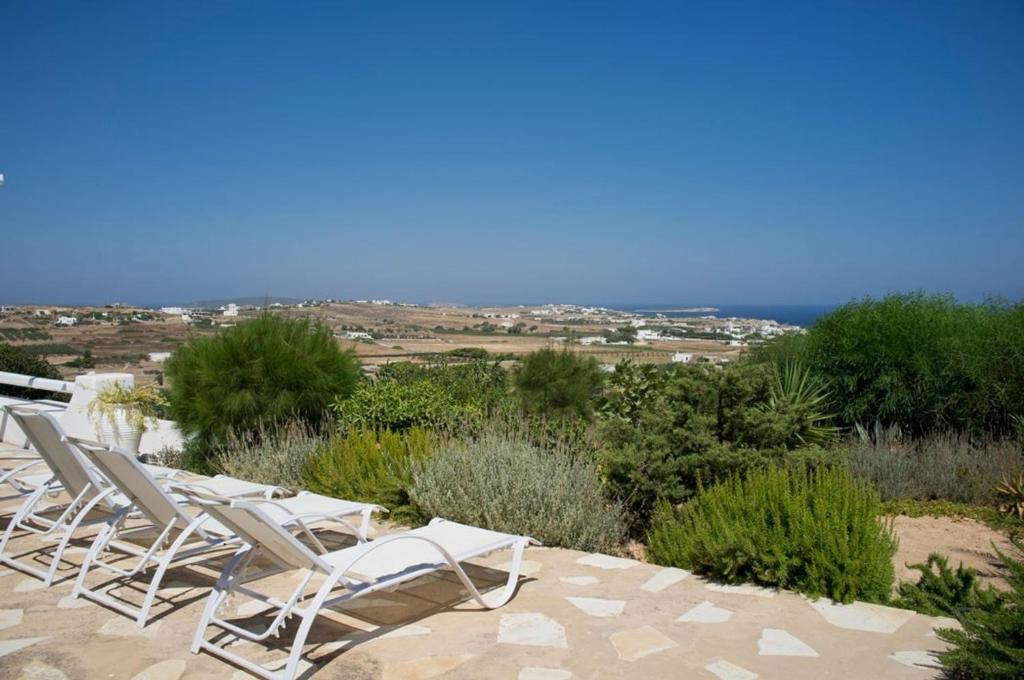 rzędu białych krzeseł siedzących na patio w obiekcie Villa Joy in Ampelas Paros w mieście Paros
