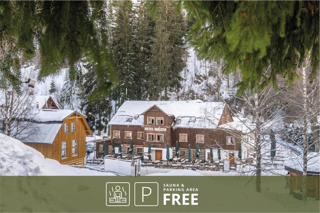 a large house is covered in snow with trees at Hotel Hvezda in Pec pod Sněžkou