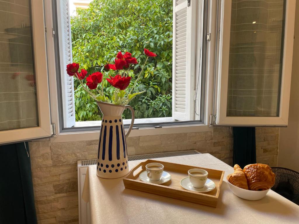 un vase avec des fleurs rouges sur une table et une fenêtre dans l'établissement Azur Studio Riviera Stay, à Antibes