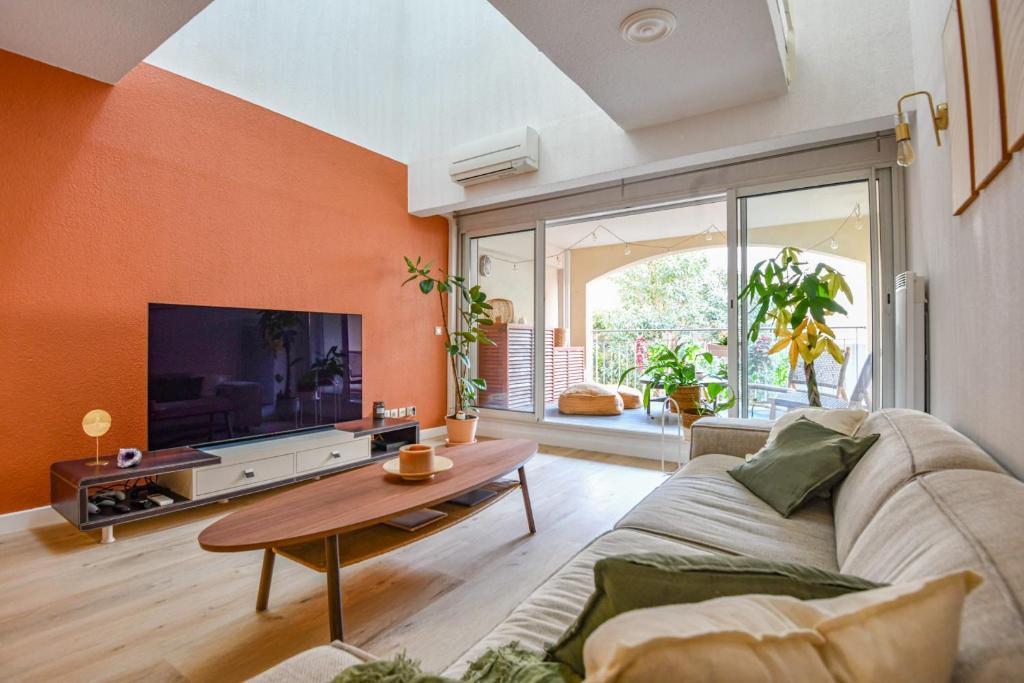 un salon avec un canapé et une télévision dans l'établissement Le Mages - Appart 2 ch avec terrasse et parking, à Marseille