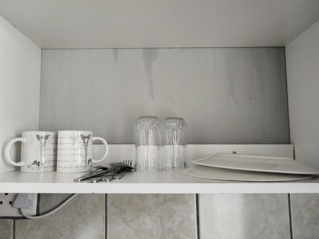a kitchen counter with glasses and utensils on a shelf at Entire rental unit in Pretoria