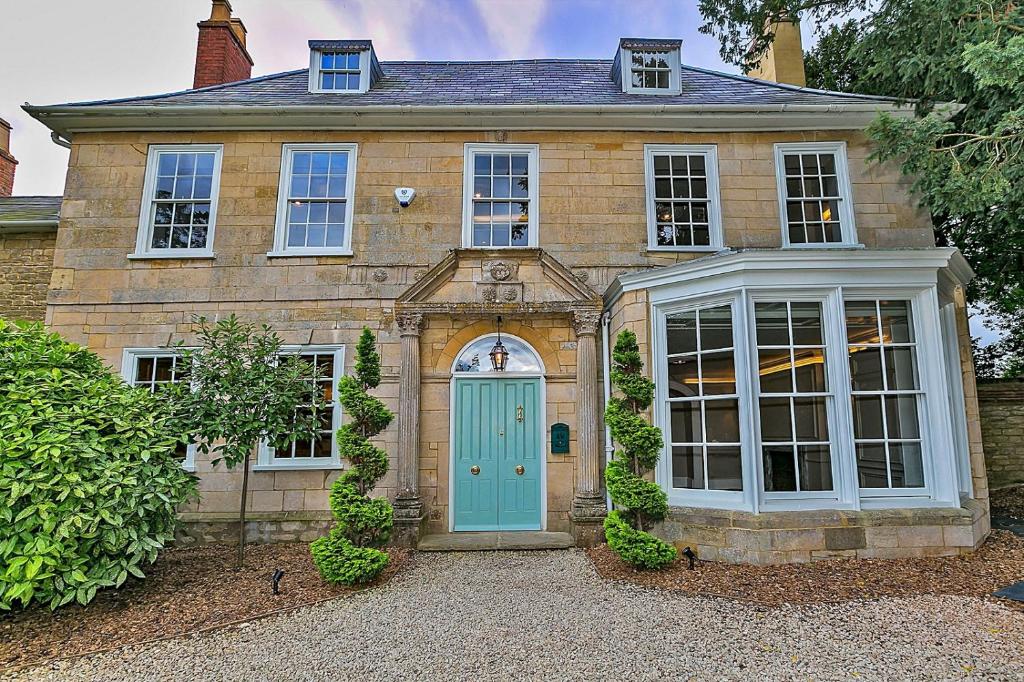 una casa antigua con una puerta azul y ventanas en Finest Retreats - Ttich Manor Retreat, en Milton Keynes
