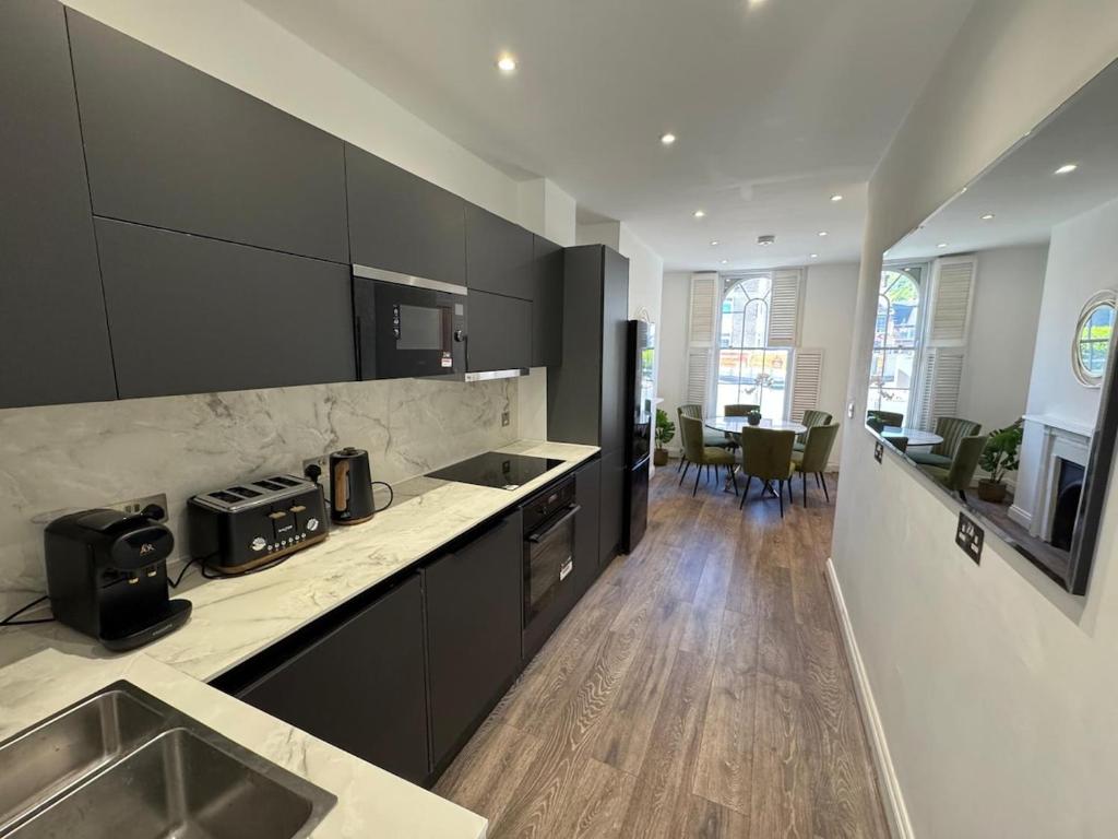 a kitchen with black cabinets and a sink and a table at Cosy Townhouse In Central London in London