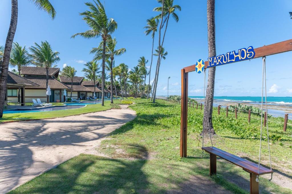 eine Schaukel am Strand mit einem Schild, das kovalam liest in der Unterkunft Marulhos Suítes Resort Muro Alto Beira Mar por Brevelar in Porto De Galinhas