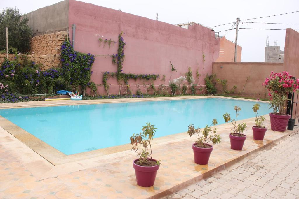 uma piscina com vasos de plantas junto a uma parede em Résidence Les Hauts de Taghazout em Taghazout