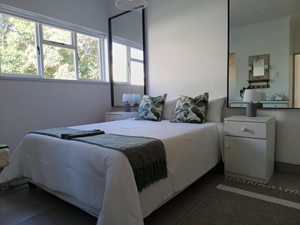 a bedroom with a white bed with a large mirror at Hartsepunt in Mossel Bay