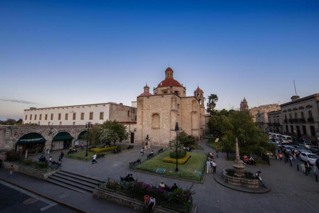 Un grupo de personas caminando por una ciudad con un edificio. en OYO Hostal Mich, en Morelia