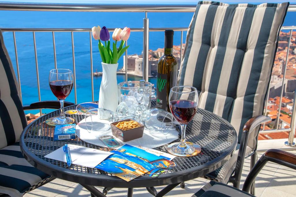 einen Tisch mit Weingläsern und Blumen auf dem Balkon in der Unterkunft Apartment Superb View 2 in Dubrovnik