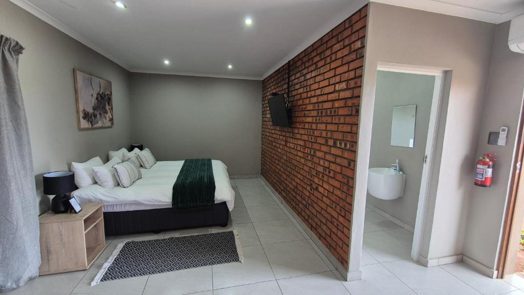 a bedroom with a bed and a brick wall at Pro Plants Accommodation in Kimberley