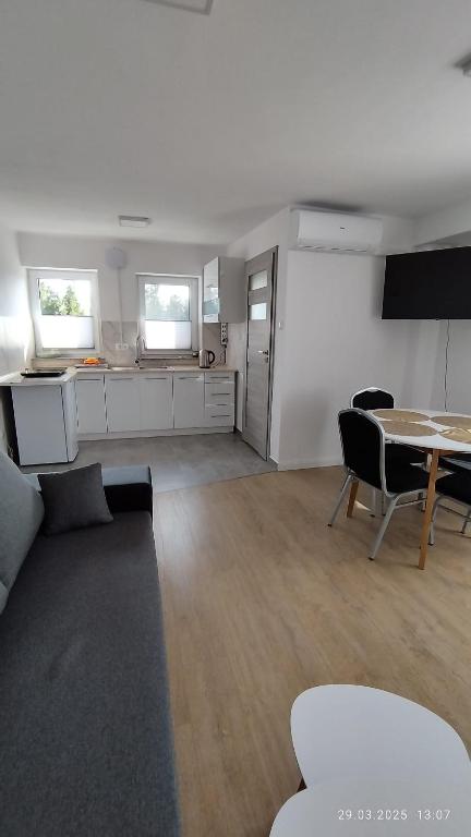 a living room with a table and a kitchen at Apartament II Na Słonku in Dzierzgoń