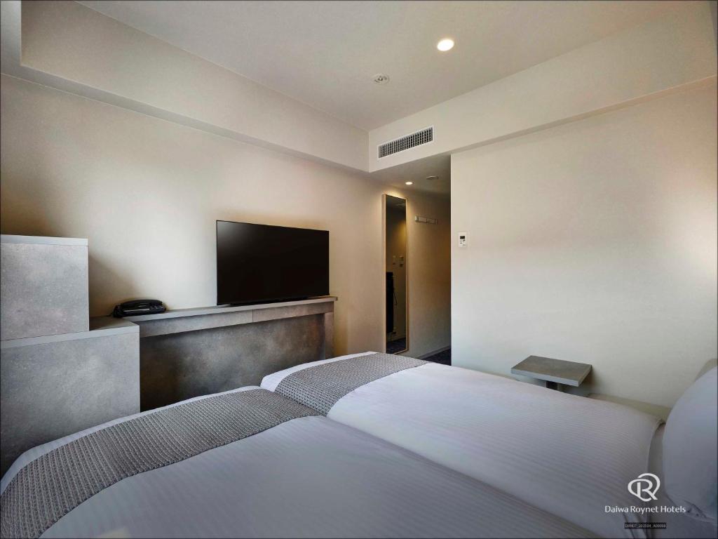 a bedroom with a bed and a flat screen tv at DEL style Fukuoka Nishinakasu by Daiwa Roynet Hotel in Fukuoka