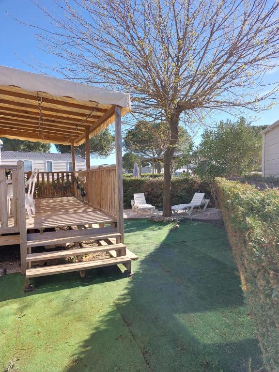 - un kiosque en bois dans une cour avec un arbre dans l'établissement KOKUA VACANCES Mobil Homes Résidentiels camping 4 étoiles Lattes, à Lattes