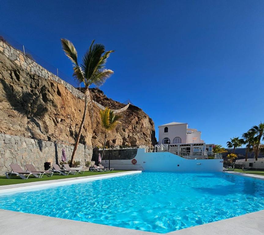 a swimming pool with a palm tree and a building at Canaima 308 in Puerto Rico de Gran Canaria
