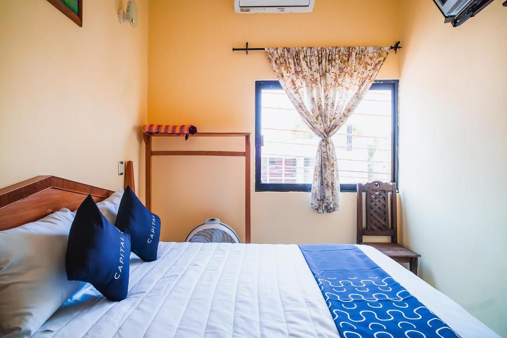 a bedroom with a bed with blue pillows and a window at Capital O Hotel Aurora, Tuxtla Gutiérrez in Tuxtla Gutiérrez