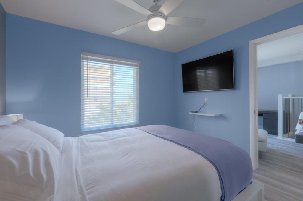 a blue bedroom with a bed with a ceiling fan at A Wave From It All Oceanview 2Nd Level Patio in Jacksonville Beach