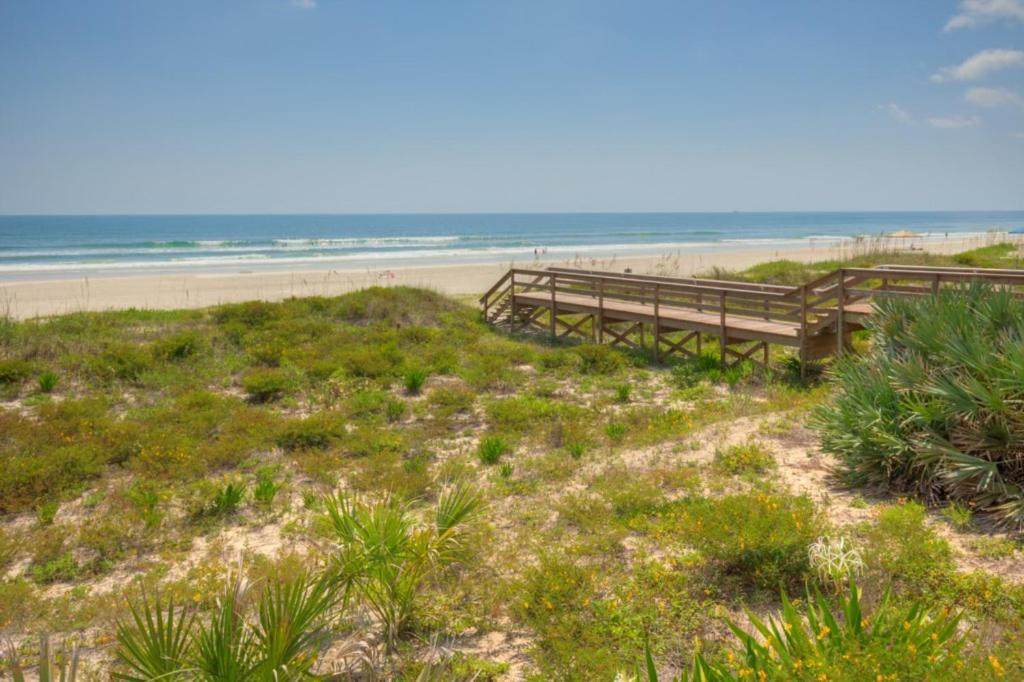 two benches on a beach with the ocean in the background at A Wave From It All Oceanview 2Nd Level Patio in Jacksonville Beach