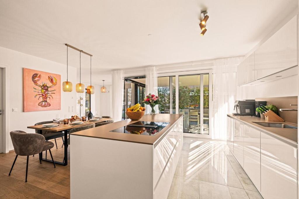a white kitchen with a counter and a table at STAYS Werft - Luxus in erster Seereihe in Kressbronn am Bodensee