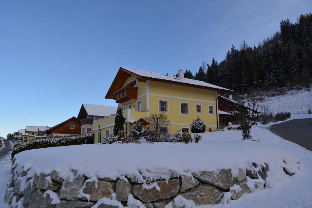 ein gelbes Haus mit Schnee auf dem Boden in der Unterkunft Apartment Krummholz in Haus im Ennstal