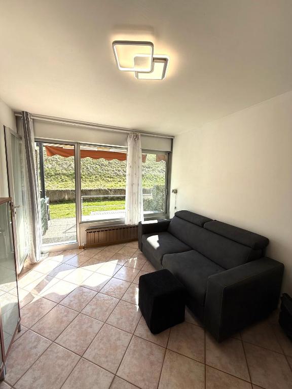 a living room with a black couch and a large window at AlpinVista- Le Maddalene in Cavareno
