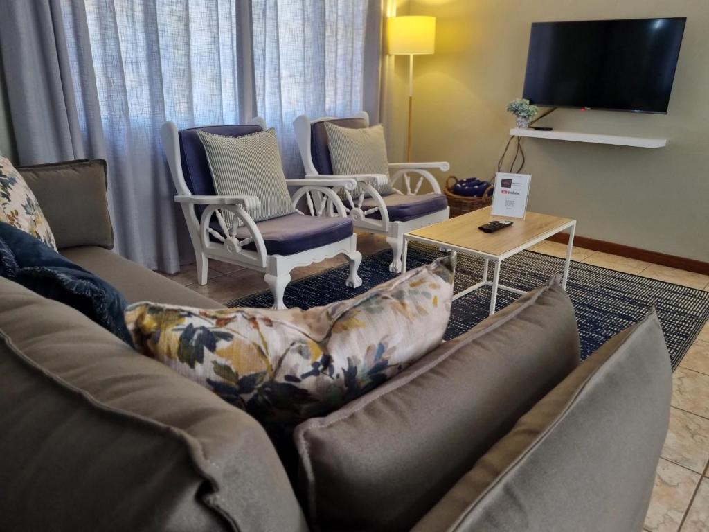 a living room with a couch and chairs and a tv at Summerville Place in Addo