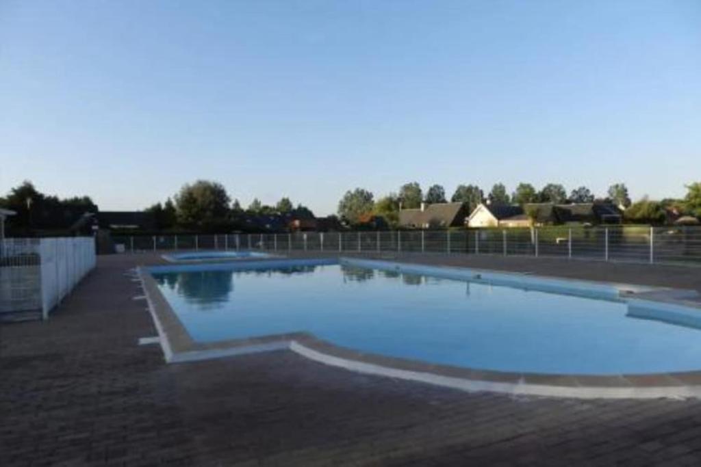 une grande piscine avec de l'eau bleue dans une cour dans l'établissement Attractive 3-rooms cottage with terrace, à Cabourg