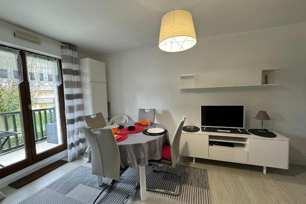 une salle à manger avec une table avec des chaises et une télévision dans l'établissement Modern apartment with direct beach access, à Cabourg