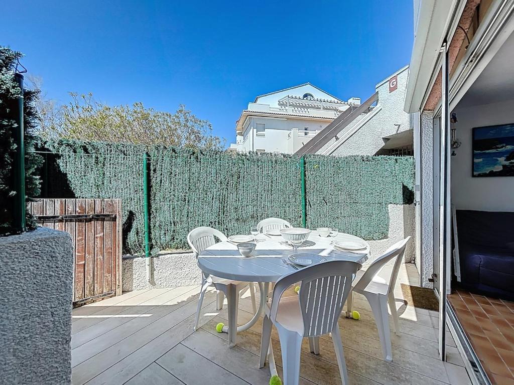 une table blanche et des chaises sur une terrasse dans l'établissement 3683-Appartement en front de mer, à Saint Cyprien Plage