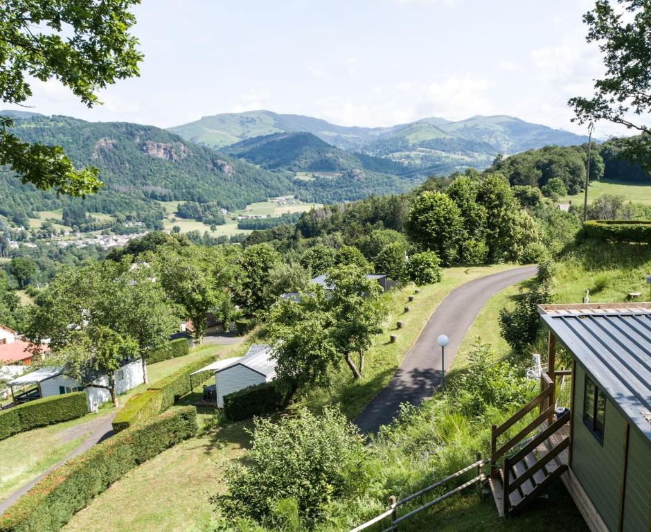 une maison avec vue sur une route et les montagnes dans l'établissement Camping la Pommeraie, à Vic-sur-Cère