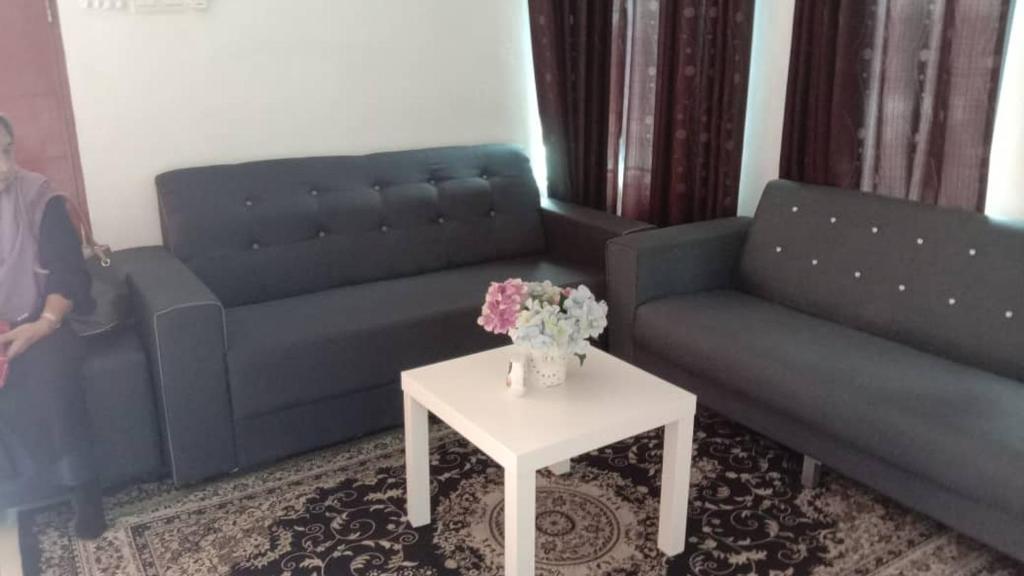 a living room with two couches and a table with flowers at Homestay Haji Ismail selayang 2025 mvslim only 3R2B in Batu Caves