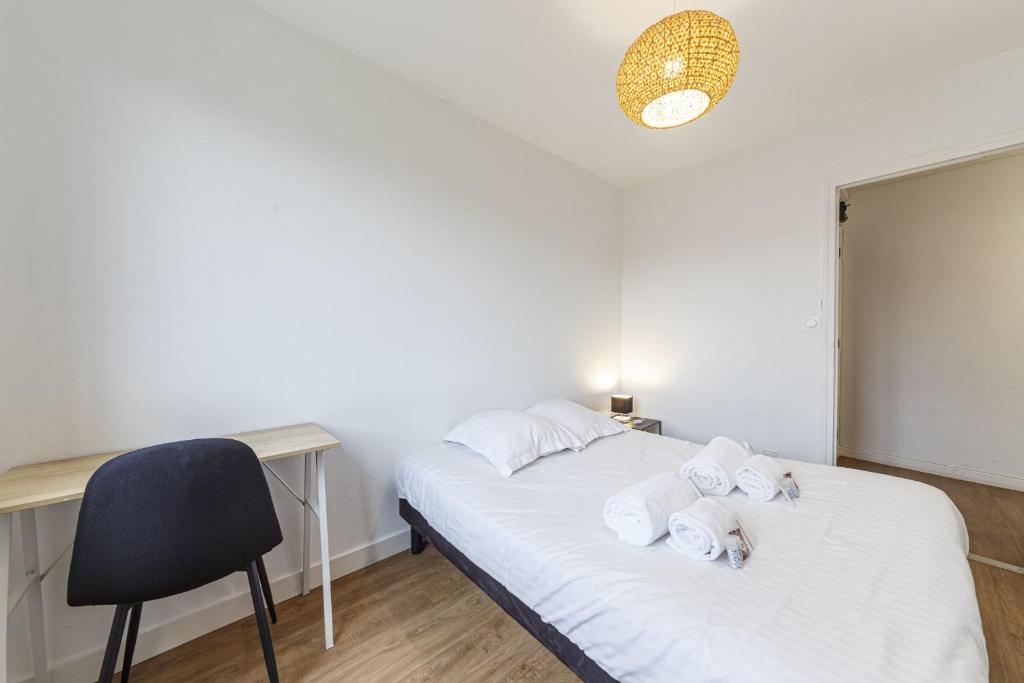 sypialnia z 2 łóżkami, biurkiem i krzesłem w obiekcie Le Mermoz Wifi Balcon Parking w mieście Laval