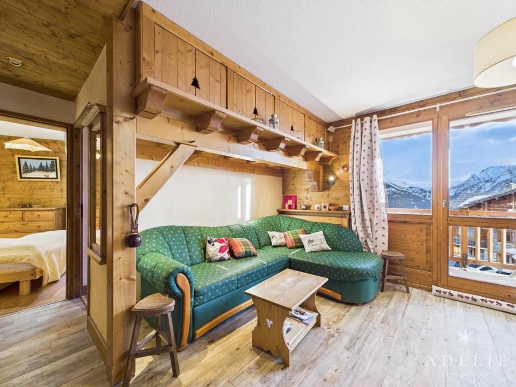 a living room with a green couch and a bed at Charmant 3P Centre Station avec Parking et TV - FR-1-398-559 in La Rosière